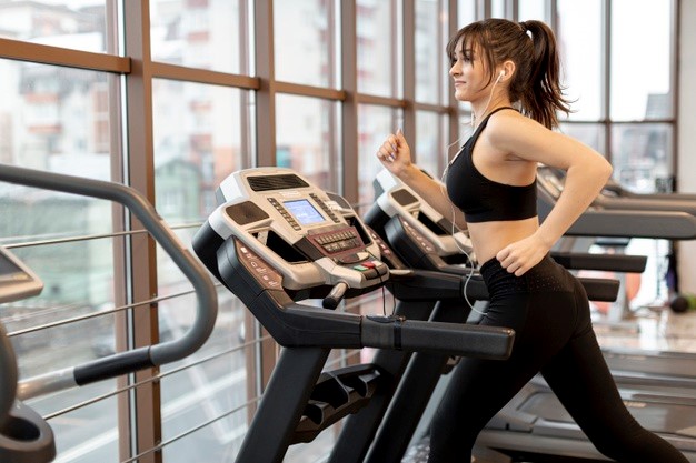 Young female running on treadmill Free Photo