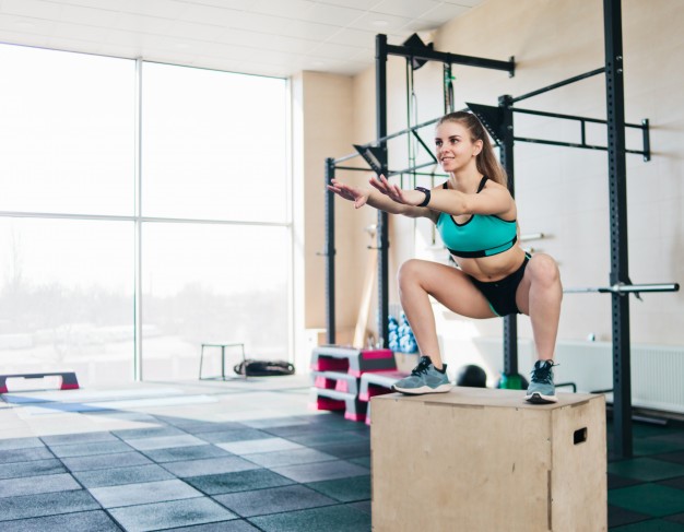 Functional modern training. young blond woman jumps in a squat on a tall wooden box Premium Photo